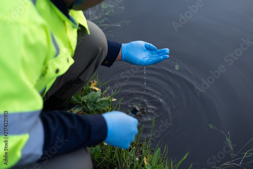 Environmental field worker inspecting water for pollution and contamination in a natural waterway.