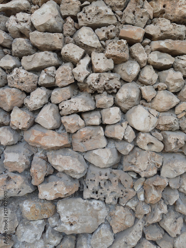 Foto Rough limestone dry stone wall texture with weathered porous rocks