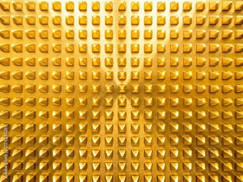 Full frame close up view of golden brass metal surface featuring 3D studded pyramid spike grid pattern for luxury background and abstract texture design