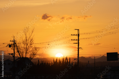 Sunset behind utility poles and power lines in a suburban neighborhood