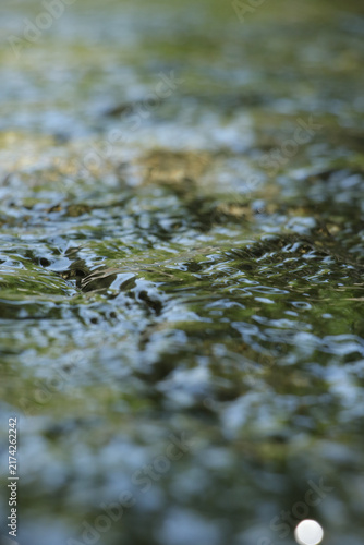 Foto Clear river water with sunlight reflections and stones