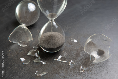 Картината върху платно Broken hourglass with black sand spilled on a dark surface