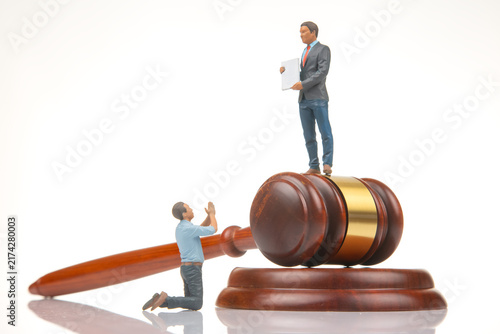 Fotografie Miniature figures on a gavel represent a courtroom scene with one figure asking