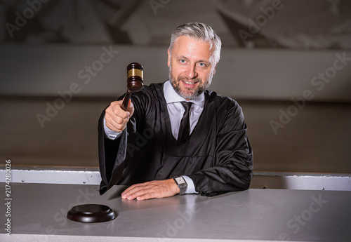Judge with Gavel Pointing in Wood-Paneled Courtroom