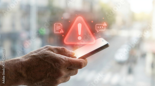 Hand holding smartphone with red warning alert icon outdoors
