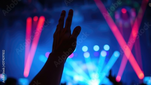 A single silhouette of a hand raised in the air against blurred red stage laser lights. Minimalist music concert backdrop, nightlife entertainment show, festival party.