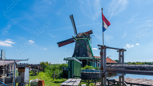 A dutch countryside landscape with a flagpole standing in front of an old windmill