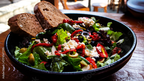 Italian Chopped Salad features vegetables such as tomatoes and lettuce, a sprinkling of Parmesan or provolone cheese, and sliced ​​olives and sourdough bread
