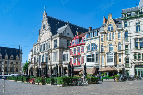 Foto Colorful gabled facades and outdoor cafes line historic Ghent square under brill