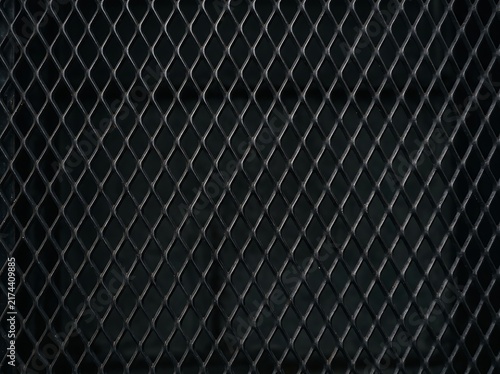 Expanded metal mesh with a diamond pattern forms a dark industrial background.