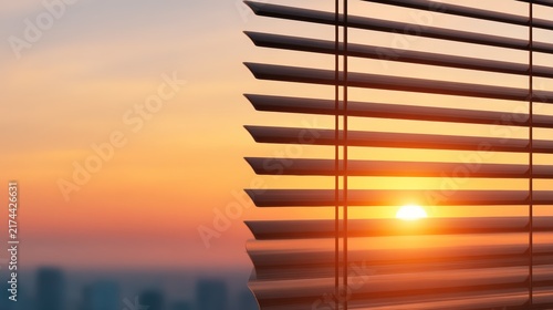 A vibrant sunset viewed through partially closed window blinds, casting warm light and shadows indoors.