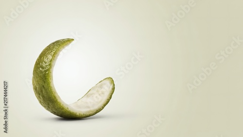 A single curled strip of lime peel isolated against a soft light background with curved piece green lime zest stands plain light surface copy space