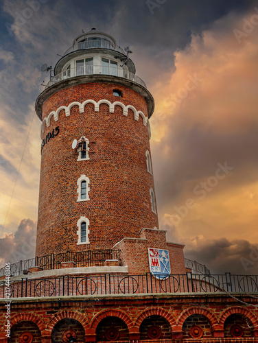 Canvas Print Historic Brick Lighthouse Tower at Sunset With Dramatic Sky and Maritime Beacon