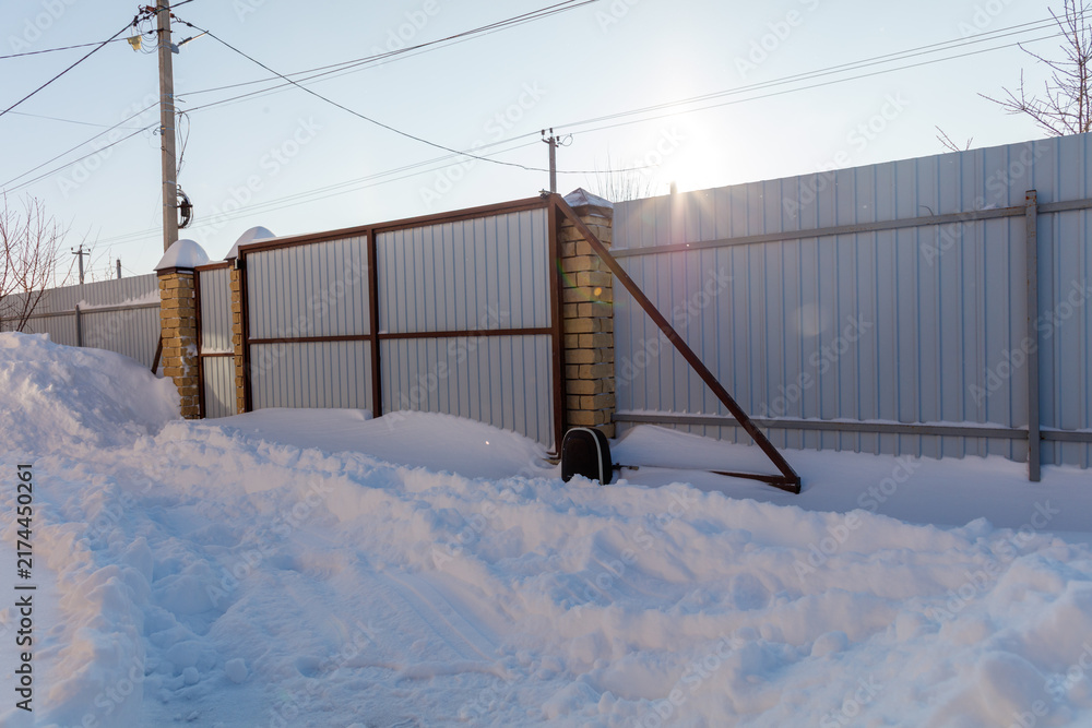 Naklejka premium Snowy fence stands beside deep winter snowbank