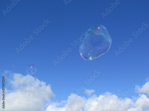 фотографія Bulles de savon transparentes flottant dans un ciel bleu nuageux
