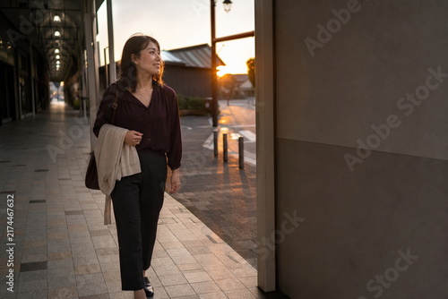 Tapety artystyczne 夕暮れの商店街を歩く女性の秋の帰宅風景