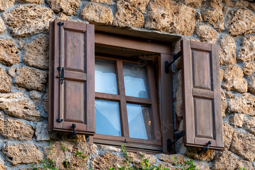 Rustic stone wall window with wooden shutters on traditional building facade