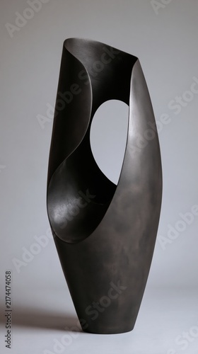 Abstract sculptural vessel crafted from dark metal featuring organic curves and a central circular opening.