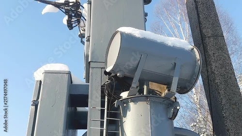 A snow-covered outdoor electrical transformer installed next to a concrete power line pole in a rural area.