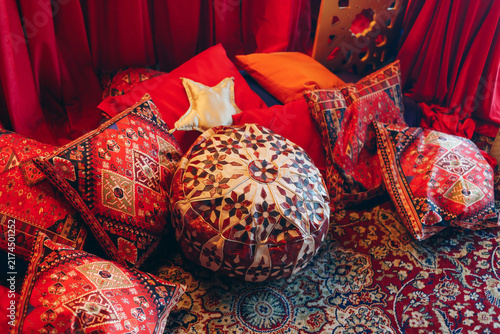 Colorful Oriental-Style Pillows And Pouf Create Cozy Bohemian Seating Area. Traditional Decorative Cushions With Ornate