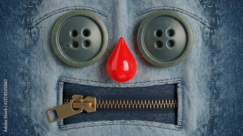 Denim fabric face with button eyes and zipper mouth, creative textile character art, blue jeans material with red drop nose