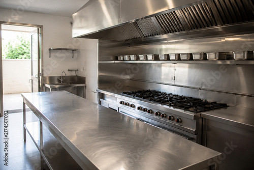 Stainless steel commercial kitchen with worktable and gas range, professional food service and culinary workspace concept