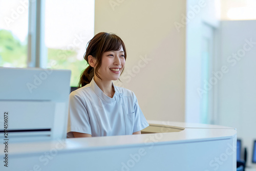 明るいクリニックの受付カウンターに座る日本人の女性スタッフ

