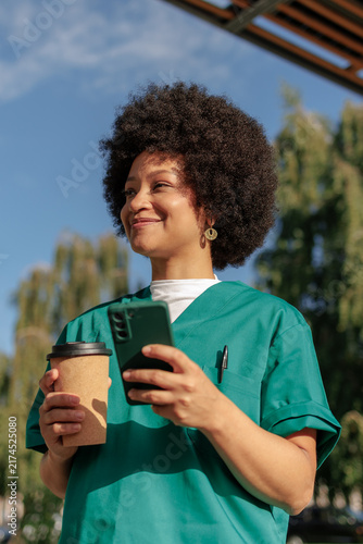 Smiling african american medical worker enjoying a break with coffee and phone