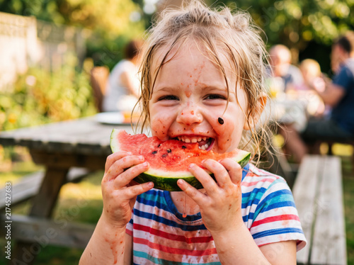 Closeup portrait of funny hungry child eating fresh juicy red watermelon slice outdoor summer food
