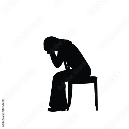 Depressed person silhouette sitting alone on a chair with head bowed down.