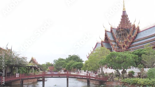 traditional thai palace pavilion featuring tiered roofs and a central spire beside a calm garden pond