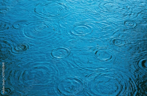 Concentric rings ripple across a deep blue water surface