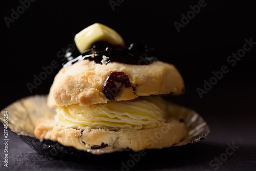 Close-up of homemade scone stuffed with cream cheese and topped with rich blueberry sauce, served on a dark background