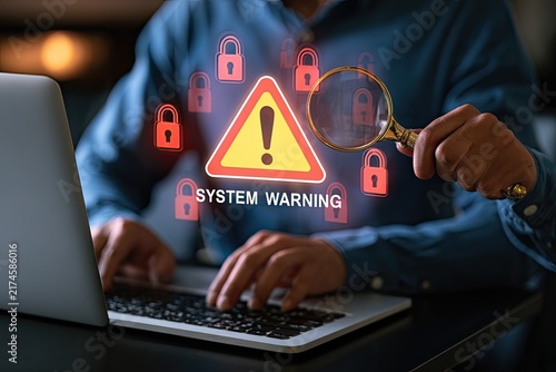 Cybersecurity Warning System Alert with Magnifying Glass Over Laptop.