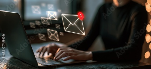 Person typing on laptop with email icons floating around, representing digital communication and online messaging.