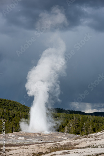 Canvas Print Old Faithful Geyser eruption beginning, dramatic stormy weather sky background,