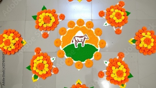 Vibrant rangoli art with central cow motif surrounded by colorful floral patterns on tiled floor