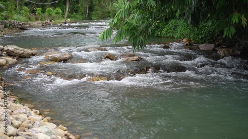 stream waterfall with rocks stones on nature clear slow motion flowing water by river rapids and camping resort in forest garden or green jungle with tourists at Saraburi Thailand for summer landscape