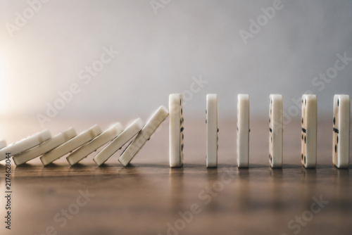 A chain of falling dominoes interrupted, focusing on the break point.