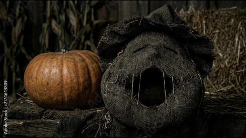 Cinematic 4K Spooky Haunted Scarecrow Screaming next to Large Pumpkin in Dark Barn Autumn Horror Atmosphere
