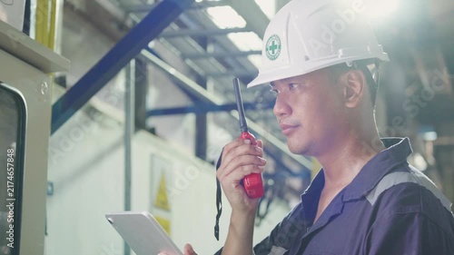 Electrical engineer is communicating with team and use radio while working on digital tablet control electrical panel in industrial plant. System PLC industrial manufacturing. Factory industry 