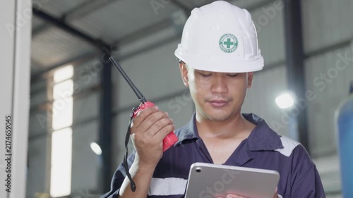 Electrical engineer is communicating with team and use radio while working on digital tablet control electrical panel in industrial plant. System PLC industrial manufacturing. Factory industry 