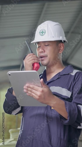 Electrical engineer is communicating with team and use radio while working on digital tablet control electrical panel in industrial plant. System PLC industrial manufacturing. Factory industry 