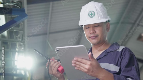Electrical engineer is communicating with team and use radio while working on digital tablet control electrical panel in industrial plant. System PLC industrial manufacturing. Factory industry 