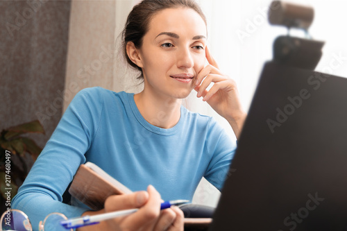Canvastavla A dark-haired woman sits at a laptop, attentively listening to a lecture