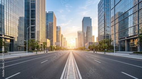 A modern city street lined with tall glass buildings at sunset with a clear blue sky