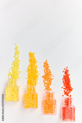 Rainbow Beads Spilling from Glass Jars on White Background