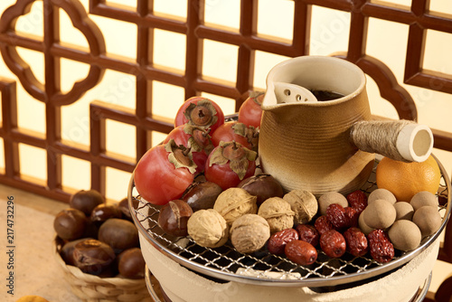 Traditional dried fruits and nuts still life with persimmons and ceramic teapot