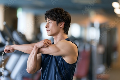 ジムでトレーニング前にストレッチをする若い男性