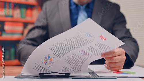 Executive conducts financial analysis reviewing corporate data, managing thorough analysis over document pages as manager completes financial analysis.